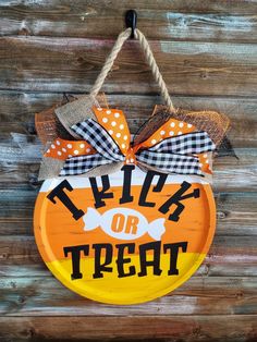 a trick or treat sign hanging on a wooden wall with burlocks and polka dots