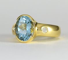 A large lovely oval aquamarine from Brazil is semi-bezel set in this minimalist 18k yellow gold ring with two flush set diamonds in the shank. Metal: 18K yellow gold The aquamarine is from Brazil and weighs 5.30 carats and measures 11.5 x 9mm oval The two 2.6mm round brilliant Diamonds have a total weight of .13 carats G-H color VS2 clarity The ring is 12.2mm wide and the shank is 5.6mm wide tapering to 3.5mm Size: 7 Aquamarine is a member of the beryl family, which also includes emerald, morgan Oval Aquamarine Ring With Bezel Setting, Oval Aquamarine Topaz Ring With Bezel Setting, Aquamarine Topaz Ring With Bezel Setting, Elegant Oval Topaz Ring With Tension Setting, Classic Oval Topaz Ring With Bezel Setting, Oval Yellow Gold Topaz Ring With Bezel Setting, Timeless Yellow Gold Oval Topaz Ring, Timeless Oval Topaz Ring In Yellow Gold, Stowe Vt