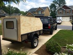 a truck with a trailer attached to it parked in front of a house next to another vehicle