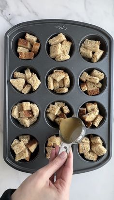 someone is pouring something into a muffin tin filled with croutons and cubes