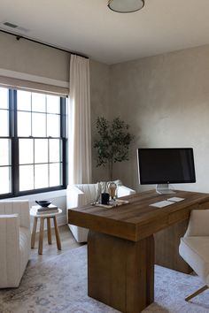 a desk with a computer on it in front of a window