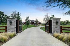 a driveway leading to two gates with grass in the foreground