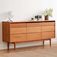 a wooden dresser sitting on top of a hard wood floor next to a white wall