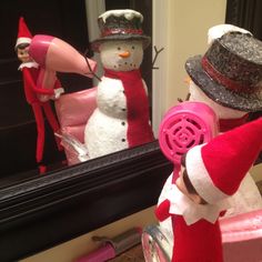 a snowman is blow drying his hair in front of a mirror with a pink blow dryer