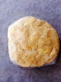 a piece of food wrapped in plastic sitting on top of a gray tablecloth covered floor