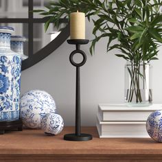 a candle is sitting on a table next to some vases and a plant in a vase