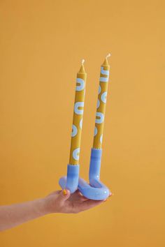 two blue and yellow candles in the shape of banana peels being held by a person's hand