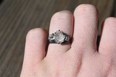 a person's hand with a ring on top of their finger, showing the center stone