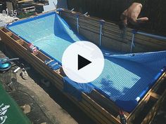 a man is standing in the back of a truck with a blue tarp on it