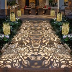 an entrance to a building with lights on the steps and flowers in front of it