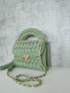 a green handbag sitting on top of a white table next to a chain strap