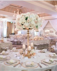 an elegant wedding reception with tall centerpieces and white flowers on the top table