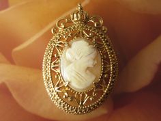 A beautiful signed Florenza cameo brooch, real carved shell portrait in an ornate goldtone setting with a crown at the very top. The backside has an attached bail if wanting to wear as a pendant by adding a necklace chain.  The brooch is 1 1/2 by 2 inch.  Mark:  Florenza In wonderful condition and ready to wear or give as a gift.  To see all the jewelry in my Etsy shop, go to my home page here ~ www.etsy.com/shop/darsjewelrybox Cameo Pendant Brooch For Wedding, Cameo Pendant Brooches For Wedding, Gold Cameo Brooch For Wedding, Gold Cameo Medallion Brooch, Gold Cameo Medallion Brooches, Elegant Gold Cameo Brooch, Formal Gold Cameo Brooches, Formal Gold Cameo Brooch, Shell Portrait