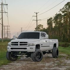 a white truck parked on top of a dirt road