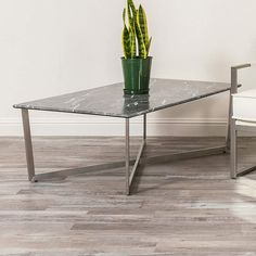 a table with a potted plant on it next to a white chair in an empty room