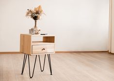 a small wooden table with two drawers on one side and a flower vase on the other