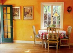 a dining room with orange walls and wooden floors