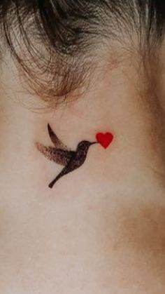 a small bird with a heart on its back side neck tattoo is seen in this image