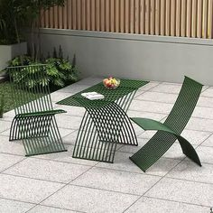 three green chairs sitting on top of a white tile floor next to a table with an apple in it