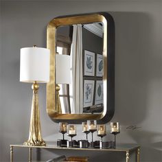 a mirror sitting on top of a table next to a lamp and lampshade