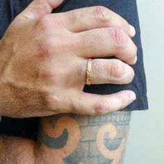 a close up of a person's hand wearing a gold ring