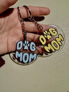 a hand holding a keychain with the words dog mom on it