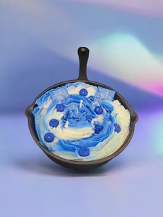 a blue and white cake in a pan on top of a table next to a blurry background