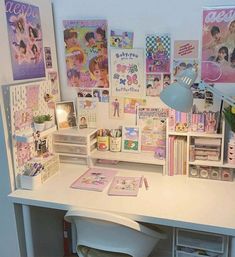 a white desk topped with lots of pictures and books next to a wall mounted poster