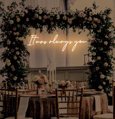 a table set up for a wedding with flowers and greenery on the wall behind it that says, there is always you