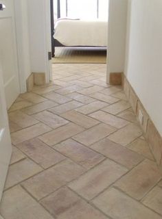 an open door leading to a bedroom with a bed in the background and tiled floor