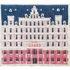 an embroidered rug with a building on the front and words grand written in red, white, and blue