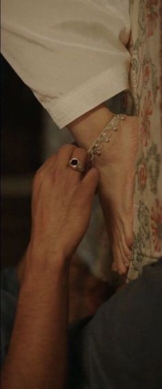 a person with their feet on the ground holding onto someone's hand while they are wearing rings