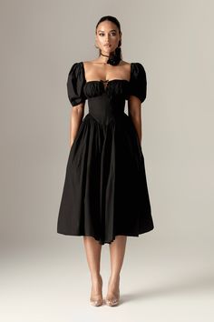 'Lynette' in black is a modern wardrobe favorite, exuding vintage charm perfect for the fall season. This dress drapes beautifully, offering an ultra-feminine silhouette with a sweetheart neckline, soft cups, and our exceptional corsetry boning to enhance the waist for a stunning shape. The perfectly structured bodice cinches the waist and is complemented by delicate puff sleeves. The layered underskirt adds volume to the skirt, which falls to a classic midi length. Crafted from cotton, a natura Sundress Black, Black Sundress, Black Kitten Heels, Dress Drape, Midi Sundress, Ultra Feminine, Feminine Silhouette, Modern Wardrobe, Fall Season