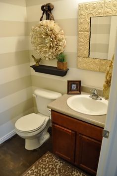 a white toilet sitting next to a sink in a bathroom under a mirror above a wooden cabinet