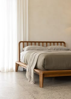 a bed with a wooden headboard and foot board in a room next to a window