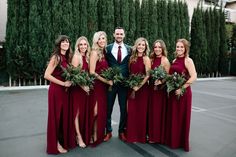 a group of people standing next to each other in front of some trees and bushes