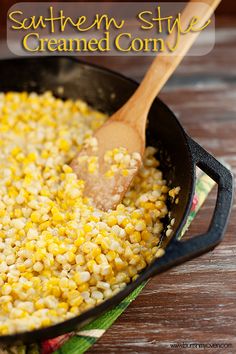 a skillet filled with corn on the cob and topped with a wooden spoon