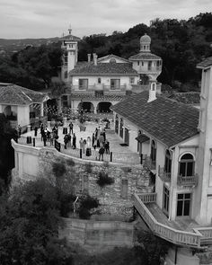 black and white photograph of people walking on a bridge in front of a large house