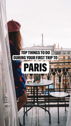 a woman standing on top of a balcony next to a table with a sign that says, top things to do during your first trip to paris