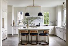 three stools sit at the center of a large kitchen island with marble countertops