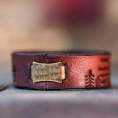 a brown leather cuff with a brass plate on it