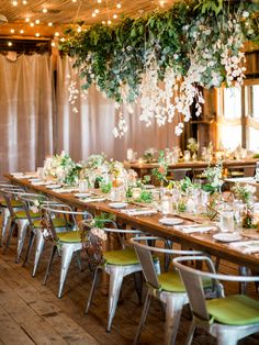 a long table with green chairs and white flowers hanging from it's centerpieces