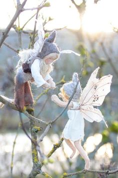 two stuffed animals sitting on top of a tree branch with leaves and branches in the background