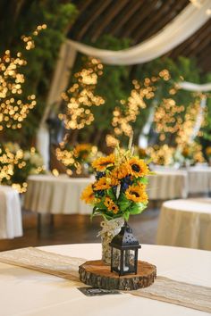 an arrangement of sunflowers in a vase on a table at a wedding reception