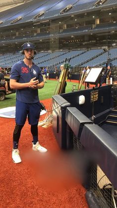 a baseball player standing on top of a field next to a batting cage and bat