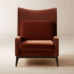 a red chair sitting on top of a white floor next to a wooden legrest