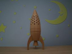 a wooden toy rocket sitting on top of a table next to a wall with stars