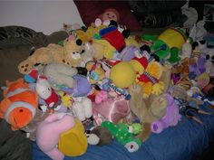 a large pile of stuffed animals sitting on top of a blue bed cover covered in blankets