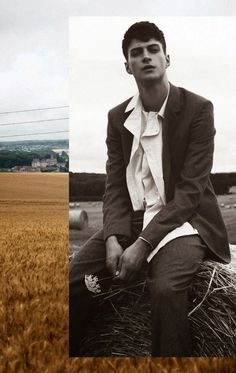 a man sitting on top of a hay bale wearing a suit and tie with his hands in his pockets