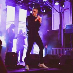 a man standing on top of a stage holding a drink